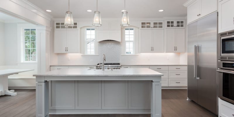 Beautiful kitchen in new luxury home with island, pendant lights, and hardwood floors